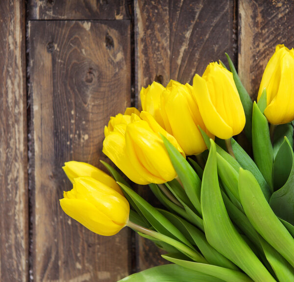 Beautiful yellow tulips on wooden background