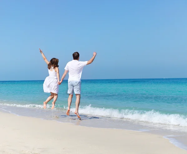 Joven pareja feliz saltando en la playa —  Fotos de Stock