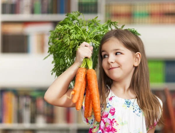 Piccola ragazza sorridente con mazzo di carote — Foto Stock