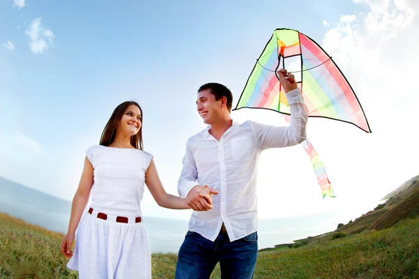 Happy young couple in love with flying a kite — Stock Photo, Image