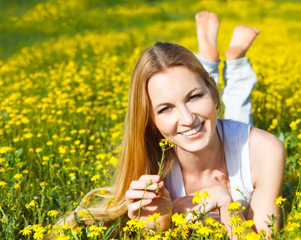 Giovane bella ragazza bionda sdraiata sul campo di fiori margherita. Ou — Foto Stock