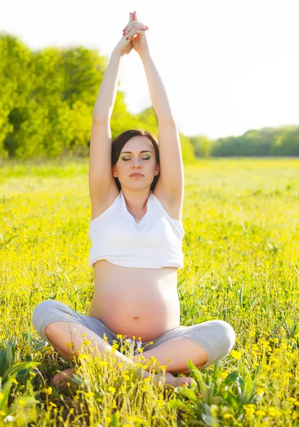 Healthy pregnant woman doing yoga in nature outdoors Stock Photo