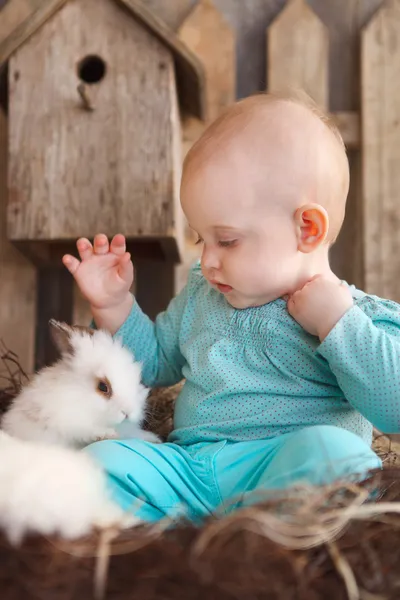 Happy little baby girl with a small white rabbit — Stock Photo, Image