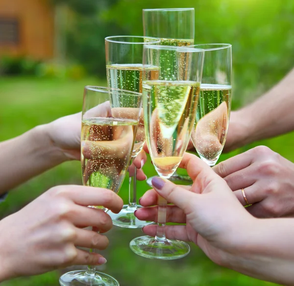 Gente sosteniendo copas de champán haciendo un brindis al aire libre — Foto de Stock