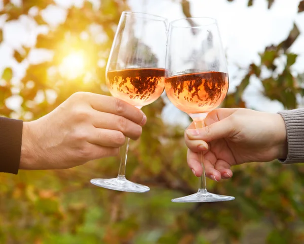 Joven pareja feliz disfrutando de unas copas de vino rosa —  Fotos de Stock