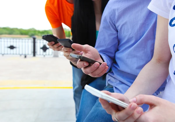 En grupp chattar med sina smartphones — Stockfoto