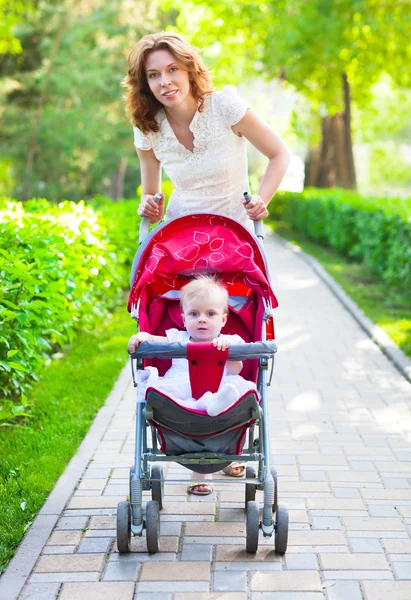 Bella mujer con su bebé en un cochecito de bebé — Stockfoto