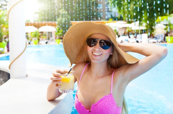 Mujer bonita en un sombrero disfrutando de un cóctel en una piscina — Foto de Stock