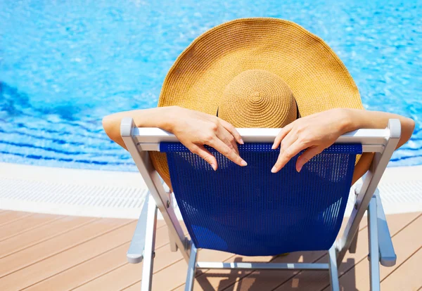 Junge Frau liegt auf Liegestuhl am Swimmingpool — Stockfoto