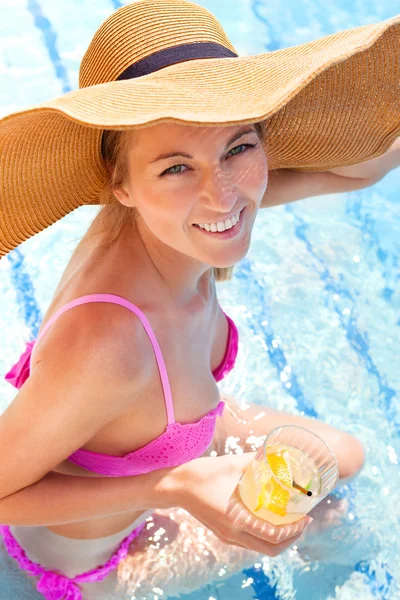 Mulher de chapéu desfrutando de coquetel em uma piscina — Fotografia de Stock
