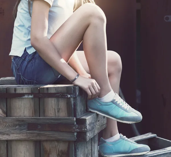 Blå sneakers på flicka ben på grunge bakgrund — Stockfoto