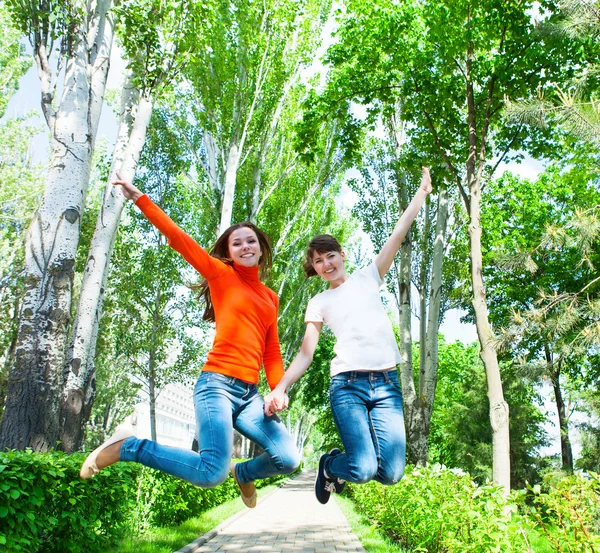 幸せなカップル十代の女の子、公園をジャンプ — ストック写真