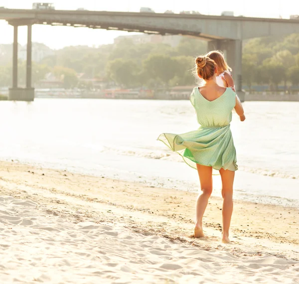 Felice madre tenendo la sua ragazza baia in spiaggia — Foto Stock