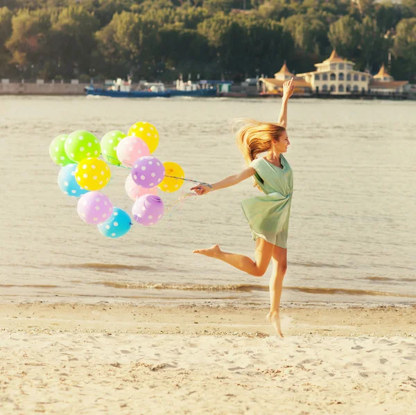 Женщина прыгает по пляжу с воздушными шарами — стоковое фото
