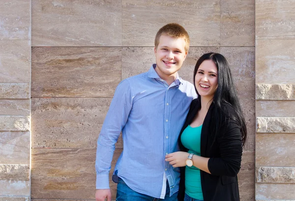 Young couple standing near the wall outdoors — Stock Photo, Image