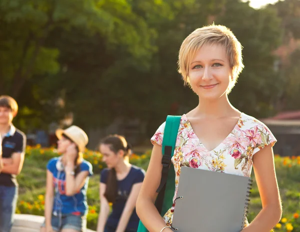 Lächelnde Studentin abends mit Freunden im Freien — Stockfoto