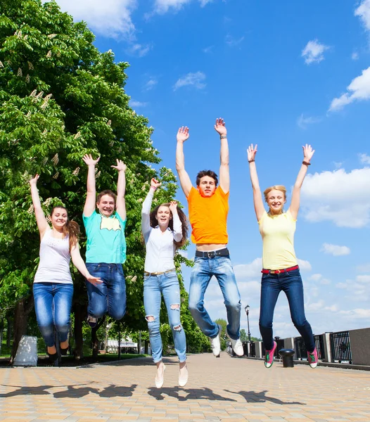 Groep van lachende tieners buiten springen Stockfoto