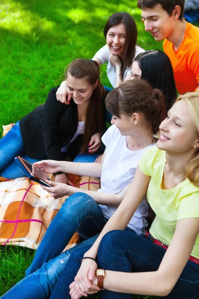 Elever som använder Tablet PC: n medan du gör läxor i parken — Stockfoto