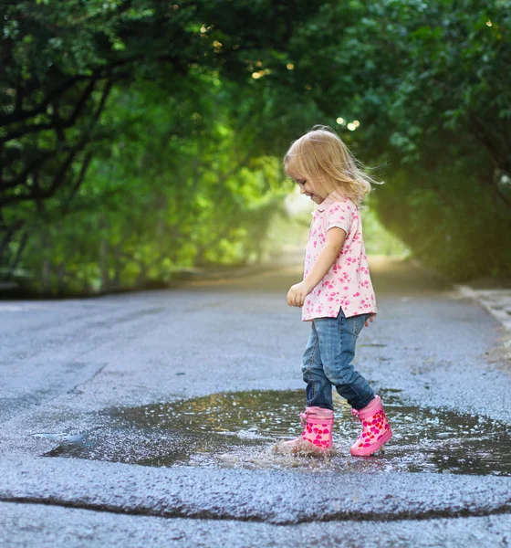 Schattig klein meisje springen in een plas — Stockfoto