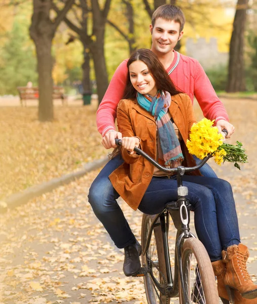 Happy couple on bicycle walking in autumn park — Stock Photo, Image