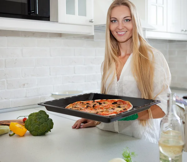 Šťastná mladá žena vaří pizzu doma — Stock fotografie