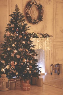 Evde Noel günü altın mücevherlerle süslenmiş yeşil kozalaklı ağaç.