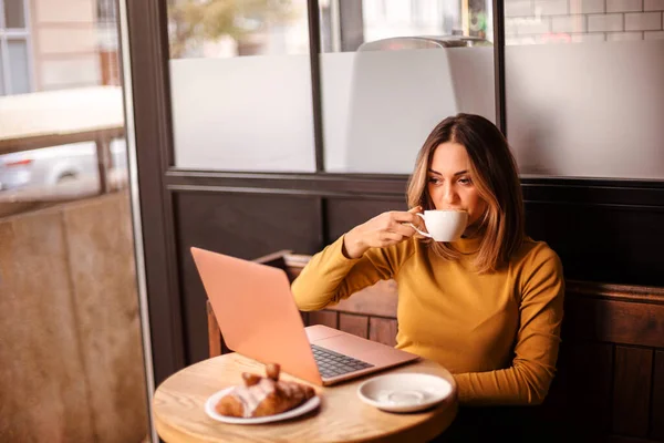 Giovane Donna Freelance Bere Caffè Mangiare Croissant Mentre Lavora Remoto — Foto Stock