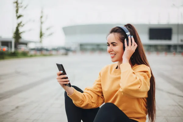 Zewnętrzne Zdjęcie Szczęśliwej Młodej Kobiety Słuchawkach Słuchającej Muzyki Smartfonie Uśmiechającej — Zdjęcie stockowe