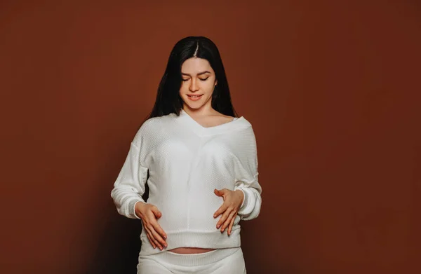 Młoda Szczęśliwa Kobieta Ciąży Długimi Brązowymi Włosami Dotykająca Brzucha Rozmawiająca — Zdjęcie stockowe