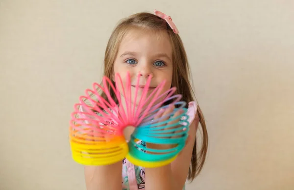 귀여운 소녀가 플라스틱 무지개 마법을 가지고 들쭉날쭉 장난감을 카메라 앞에서 — 스톡 사진