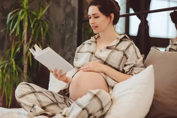 Young Attractive Happy Pregnant Woman Homewear Reading Book Touching Belly — Stock Photo, Image