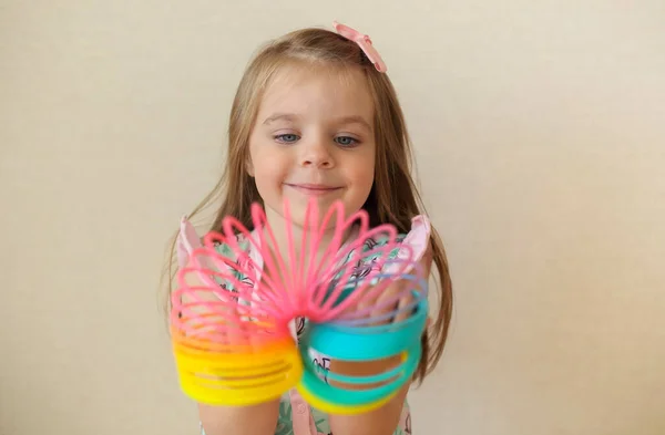 귀여운 소녀가 플라스틱 무지개 마법을 가지고 들쭉날쭉 장난감을 카메라 앞에서 — 스톡 사진