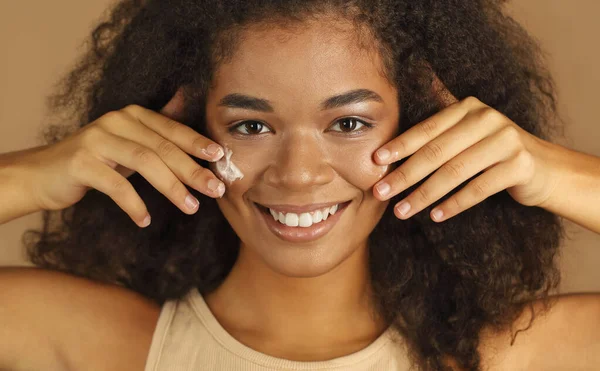 Smiling Dark Skinned Woman Curly Afro Hair Applies Face Cream — Stock Photo, Image