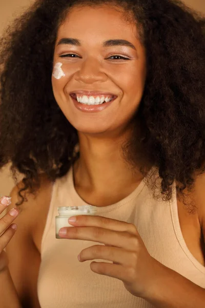 Smiling Dark Skinned Woman Curly Afro Hair Applies Face Cream — Stock Photo, Image