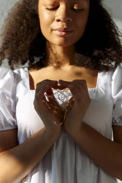感恩的非洲裔美国女人 紧闭双眼 身穿白衣 心形斑斓 手握光明 平静的黑人女性为爱情的象征 慈善概念 — 图库照片