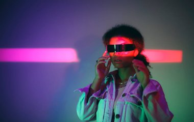 Kendine güvenen Afro-Amerikalı bir kadın sanal dünyayı keşfederken stüdyoda neon ışıklarının altında sanal gerçeklik oyunları oynuyor. Modern teknolojiler