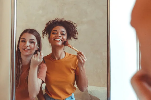 Kobieca Przyjaźń Dwie Radosne Wielorasowe Dziewczyny Nakładają Makijaż Pędzlem Dobrze — Zdjęcie stockowe