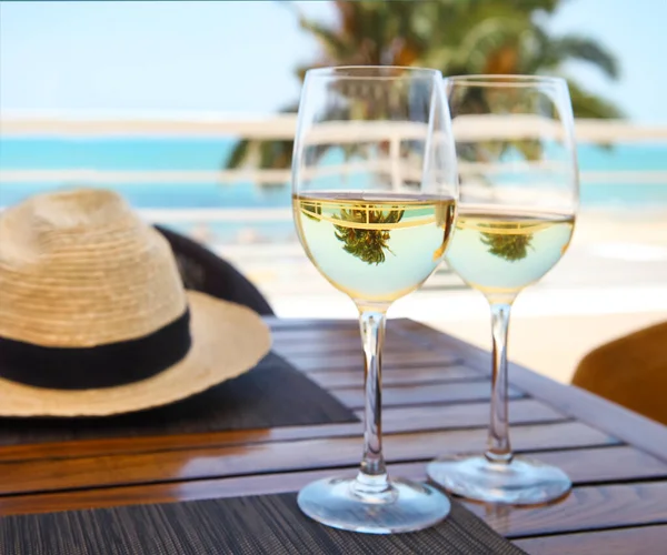 两个酒杯在桌与白葡萄酒在天空和大海背景 图库图片