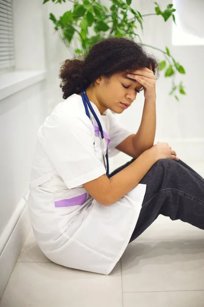 슬프게 아프리카 미국인 간호사가 표정으로 바닥에 클리닉에서 일하는 — 스톡 사진