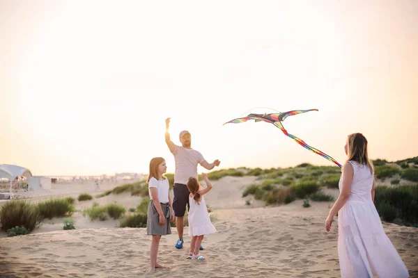与父母和孩子一起玩蛇的快乐家庭在海滩度假 夏季快乐的概念与混合种族的人在海边玩得开心 免版税图库图片