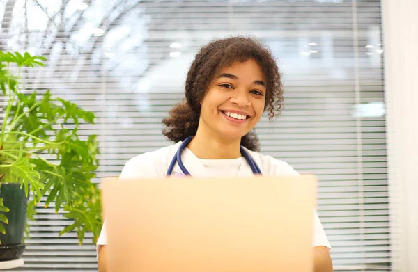 Joven Médico Afroamericano Feliz Sentado Lugar Trabajo Mirando Cámara Sonriendo —  Fotos de Stock