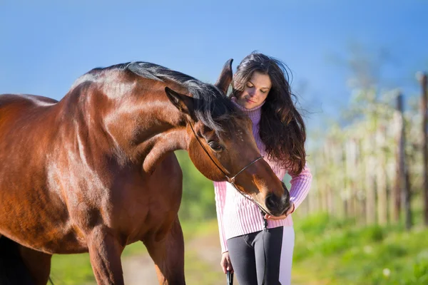 Mooi meisje permanent met een paard in veld — Stockfoto