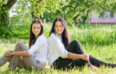 Yeşil çimenlerin üzerinde oturarak iki kız