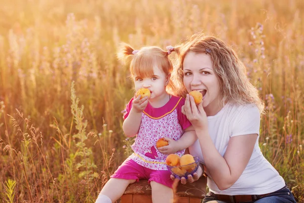 Mutter und kleines Mädchen mit Pfirsich im Freien — Stockfoto