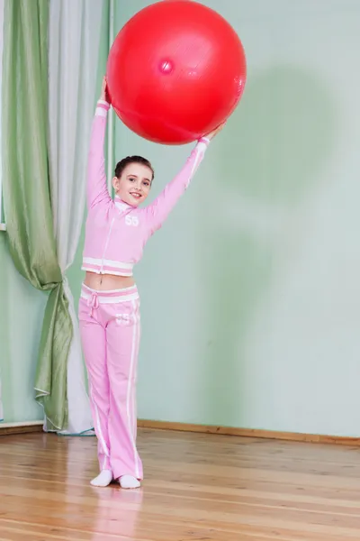 Sportive kid holding large gymnastic ball up high — Stock Photo, Image