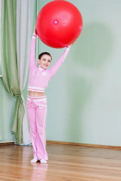 Criança esportiva segurando grande bola de ginástica no alto — Fotografia de Stock