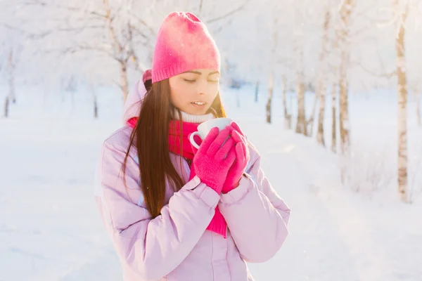 Jonge vrouw met een kop warme drank in winter park — Stockfoto