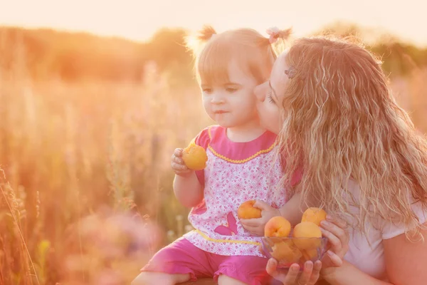 Mother and little girl with peach outdoor — Stock Photo, Image