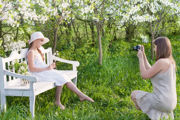 Mamma fotograferar sin dotter på vårträdgård — Stockfoto