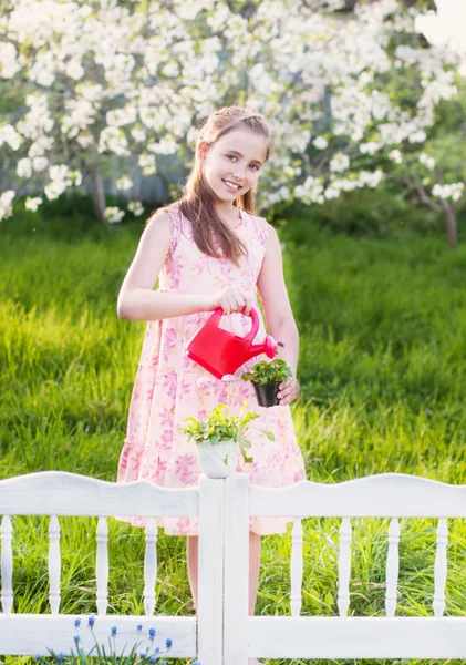 Beautiful girl watering spring flowers — Stock Photo, Image